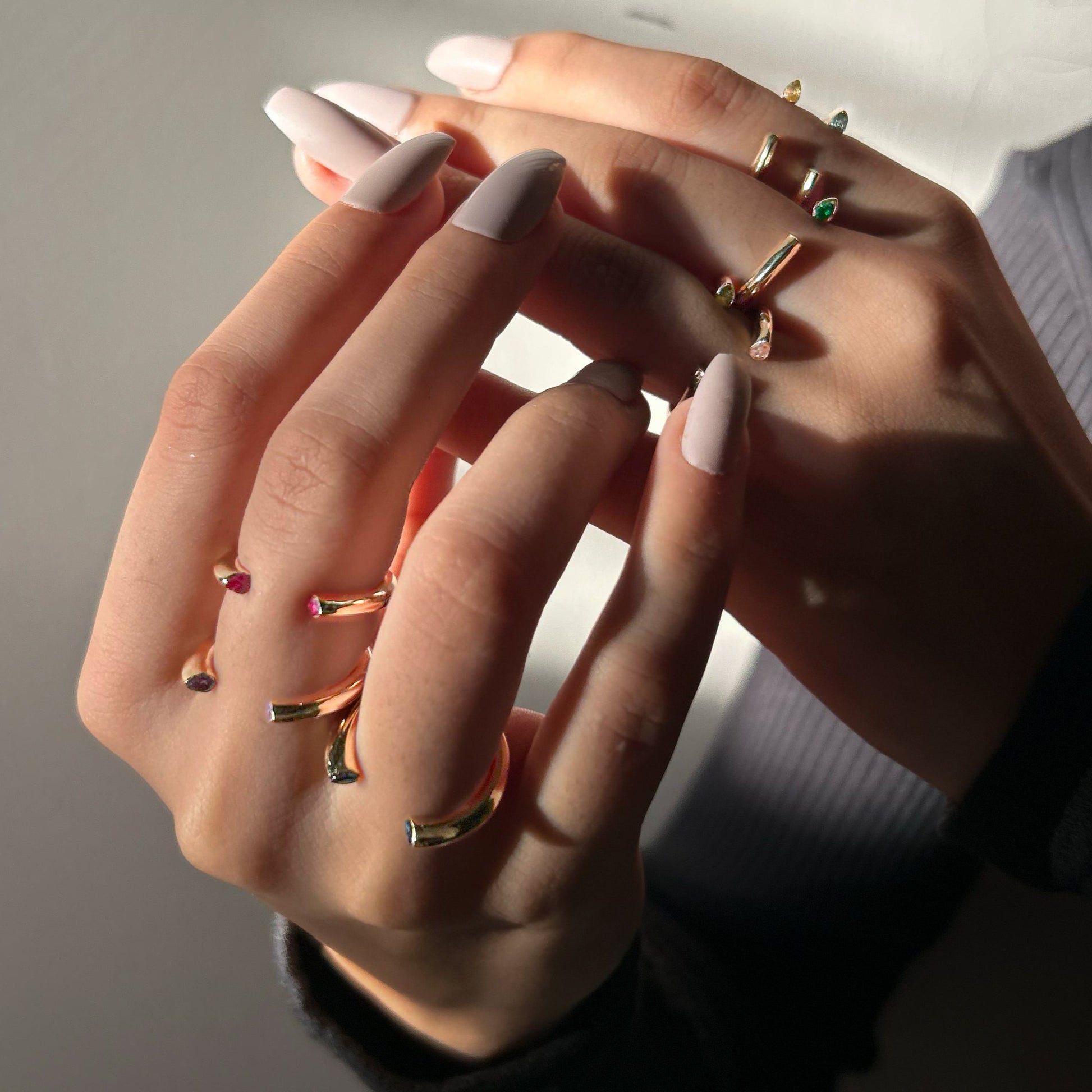 Close-up of a hand with multiple rings on a neutral background