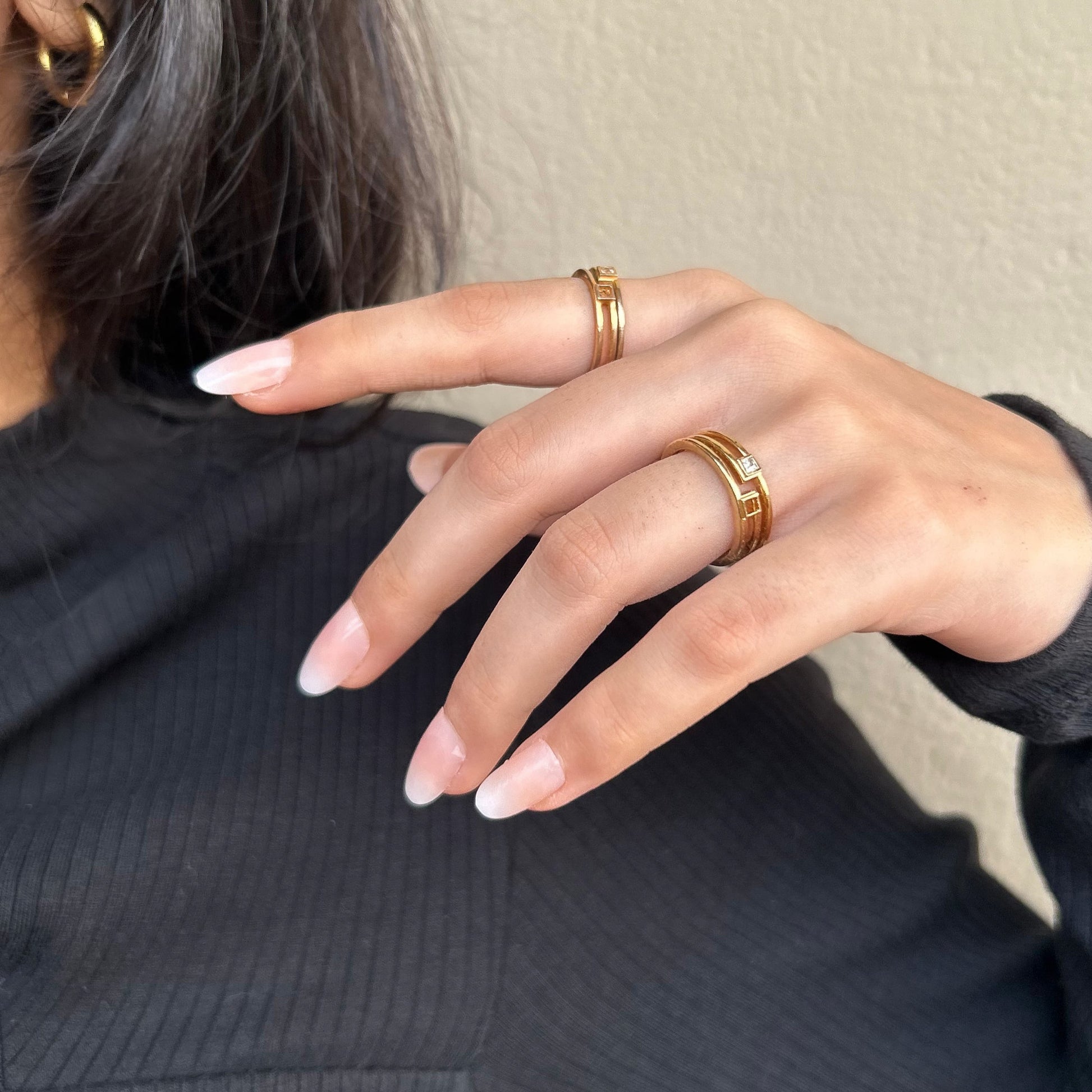 Hand with gold rings on a neutral background