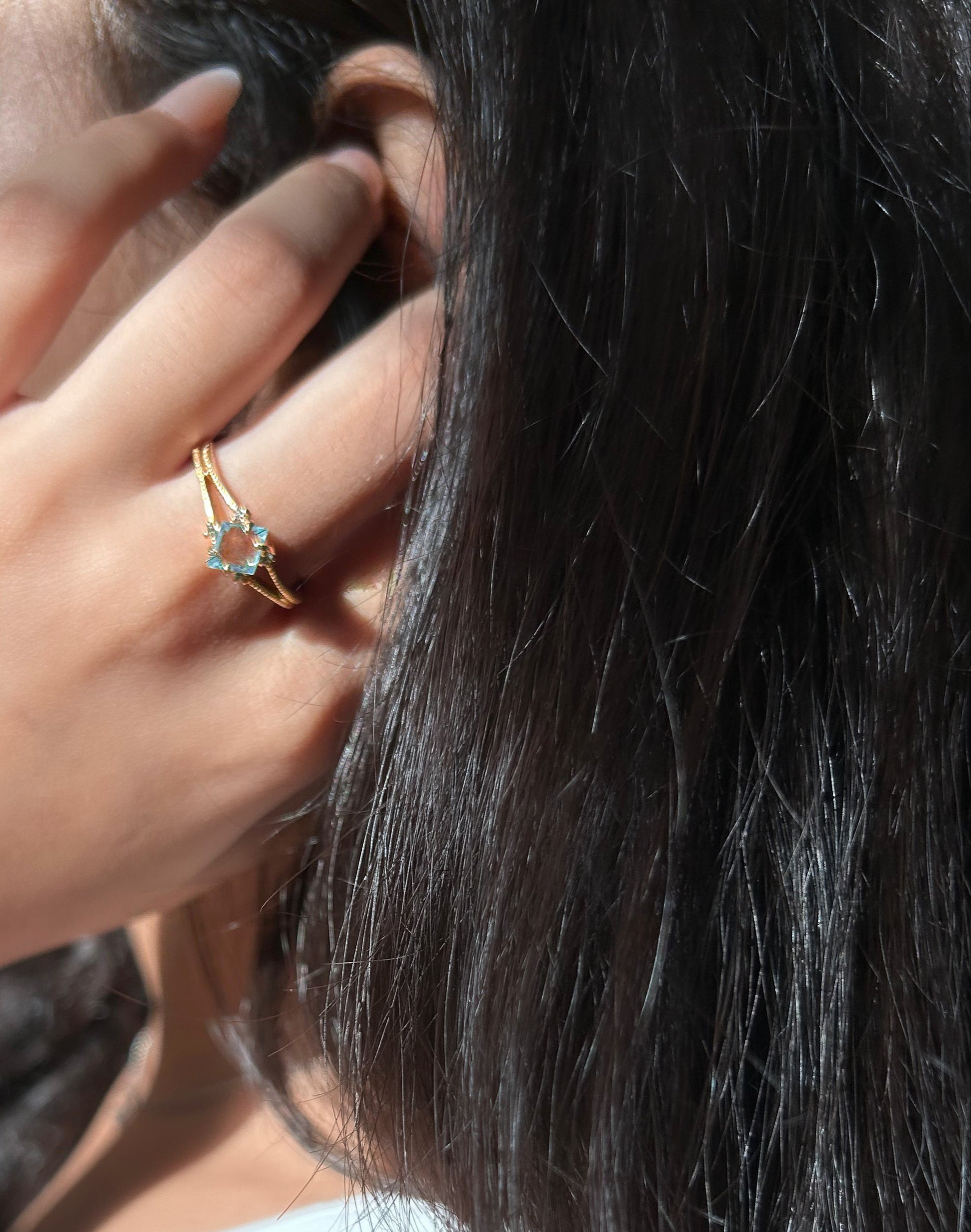Close-up of a woman adjusting her hair with a ring on her finger.