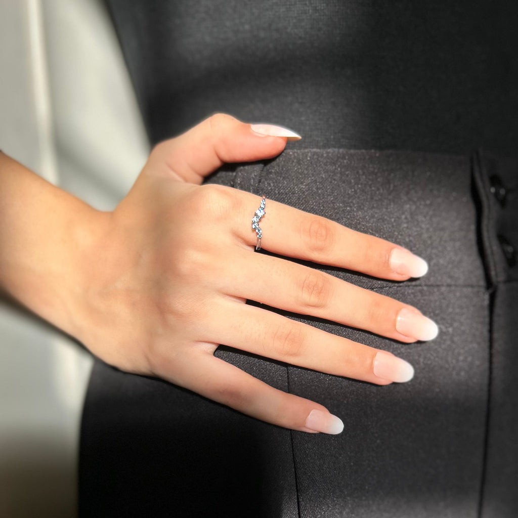 Hand wearing a silver ring with a diamond on a dark background