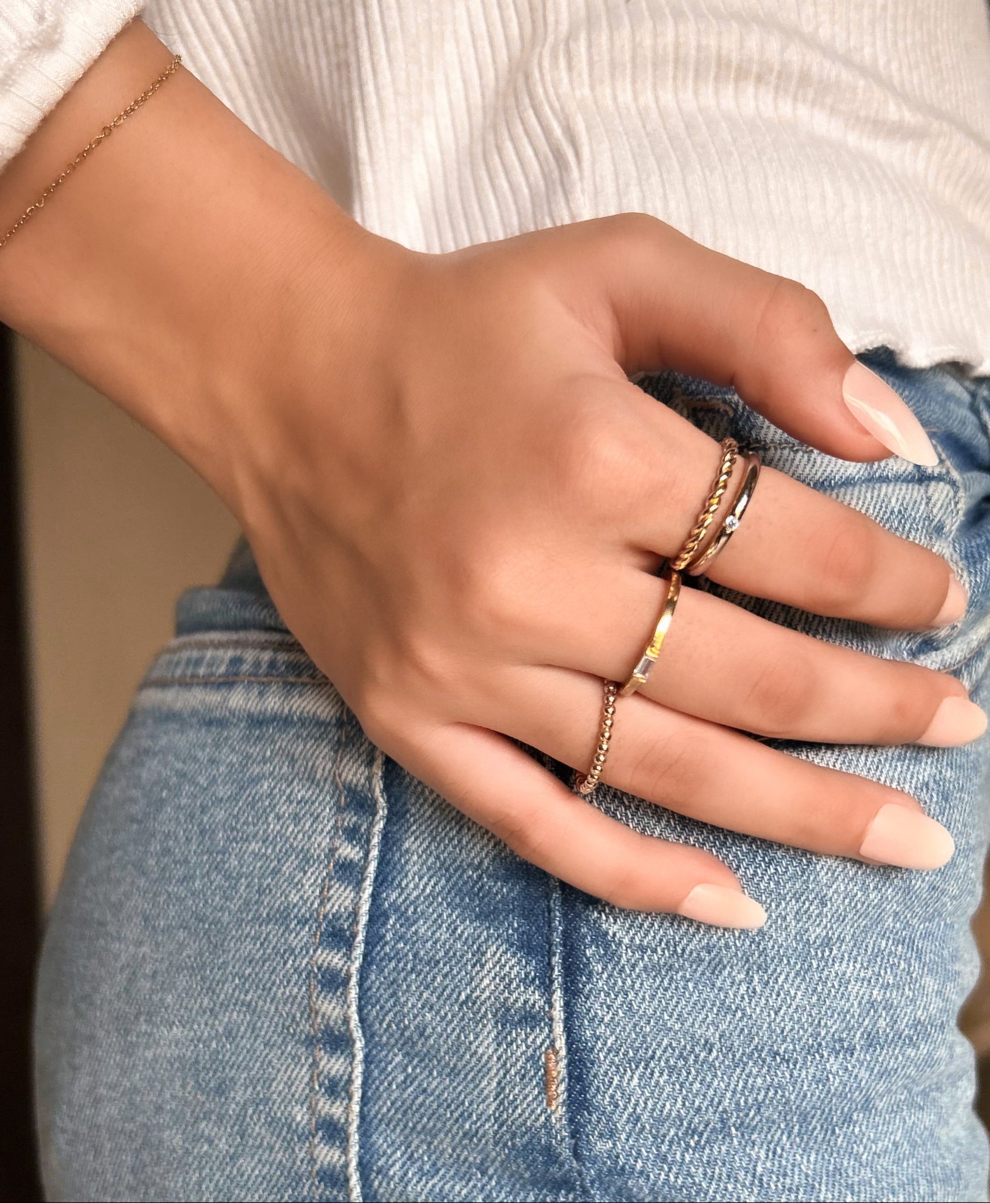 Close-up of a hand wearing multiple rings on a blurred indoor background