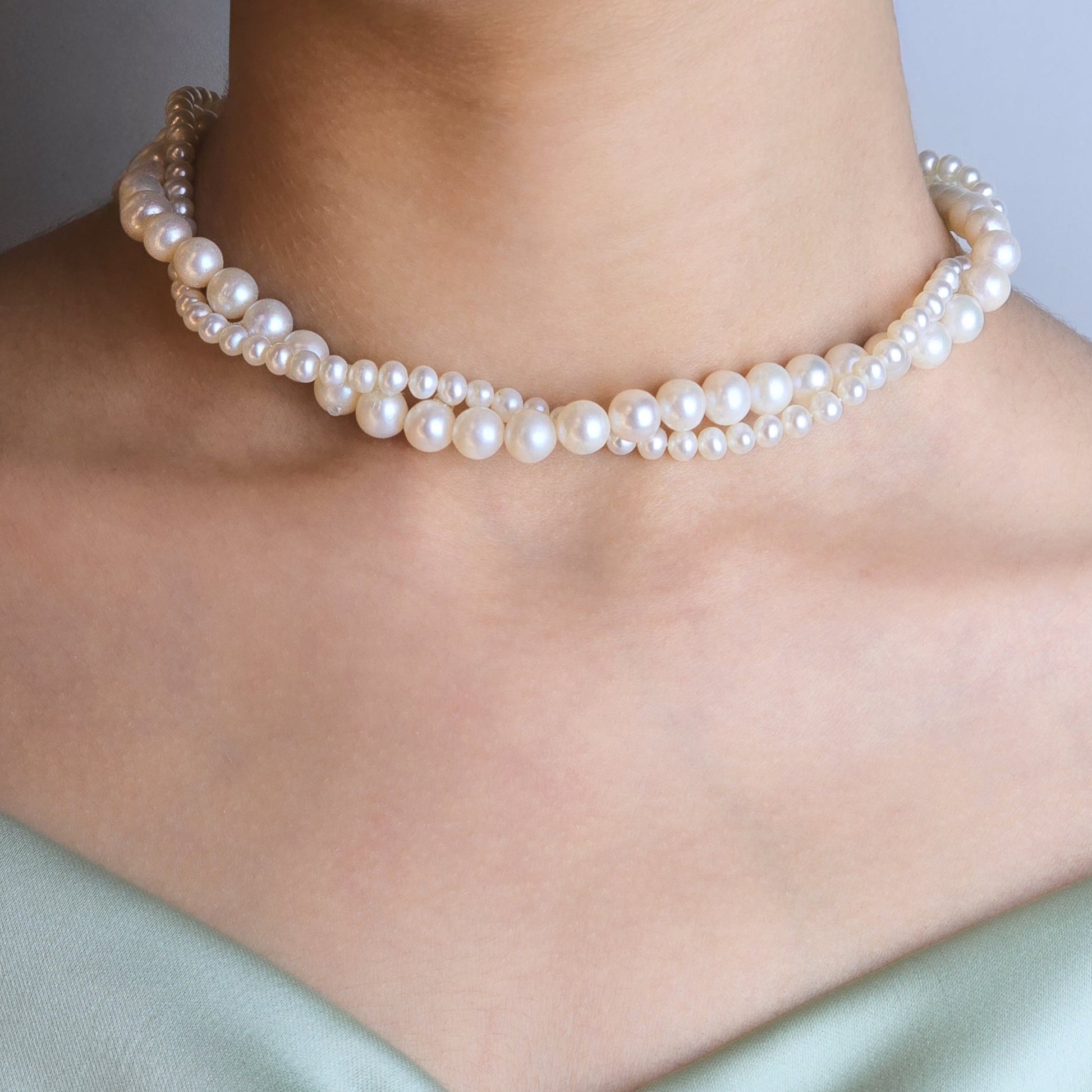 Pearl necklace worn by a person with a neutral background