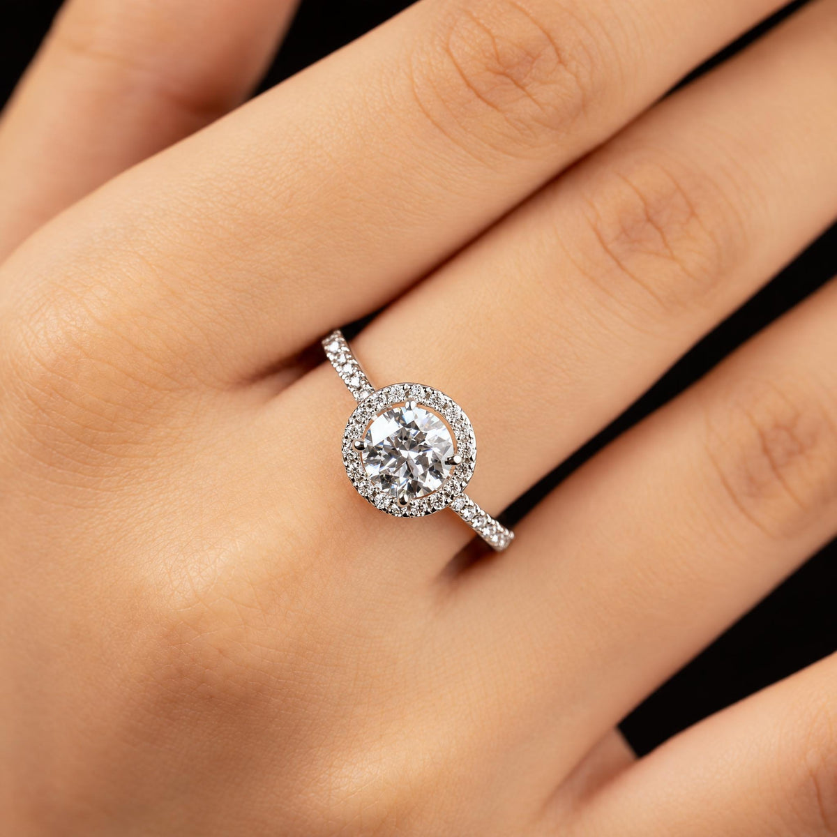 Adele ring worn on hand — round centre stone with diamond halo on a pave band