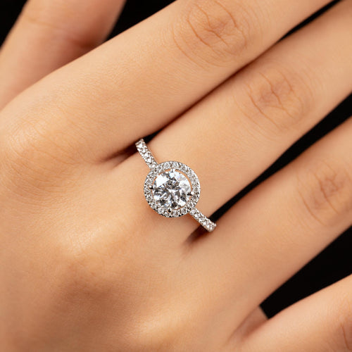 Adele ring worn on hand — round centre stone with diamond halo on a pave band