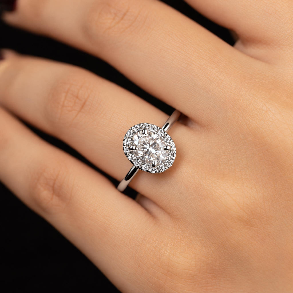 Colette ring worn on hand — oval centre stone with a diamond halo on a slim band