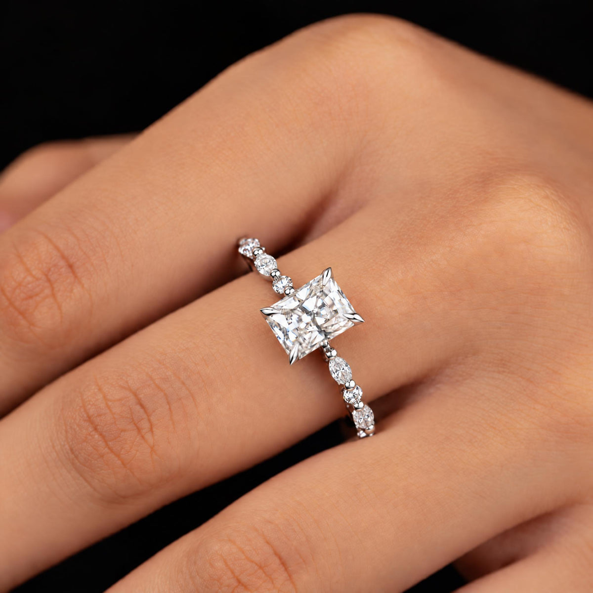 Elara ring worn on hand — high-set emerald-cut stone on a mixed baguette and round pave band