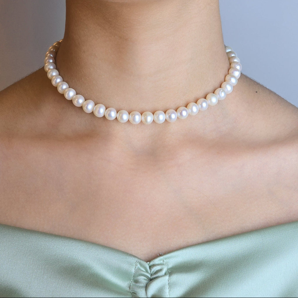 Pearl necklace worn by a person with a neutral background